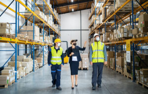 A group of workers with manager working indoors in warehouse, coronavirus concept.