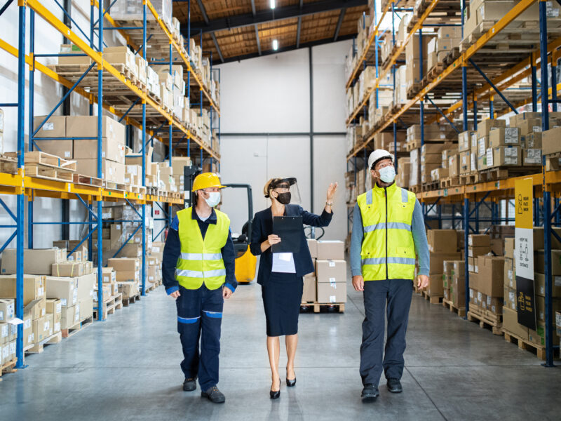 A group of workers with manager working indoors in warehouse, coronavirus concept.